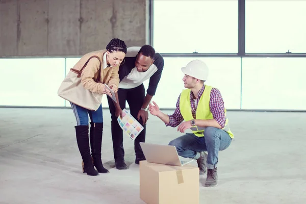 Ingeniero mostrando los planes de diseño de la casa a un joven coupl multiétnico — Foto de Stock