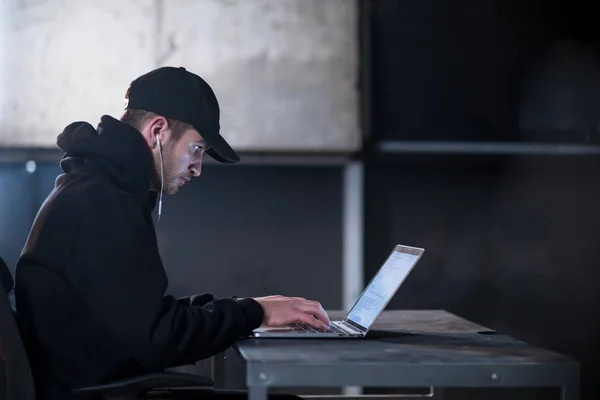 Talented hacker using laptop computer while working in dark offi — Stock Photo, Image