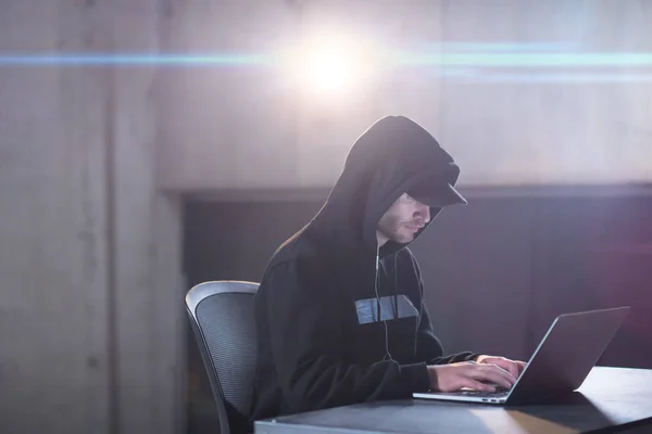 Young talented hacker using laptop computer while working in dar — Stock Photo, Image