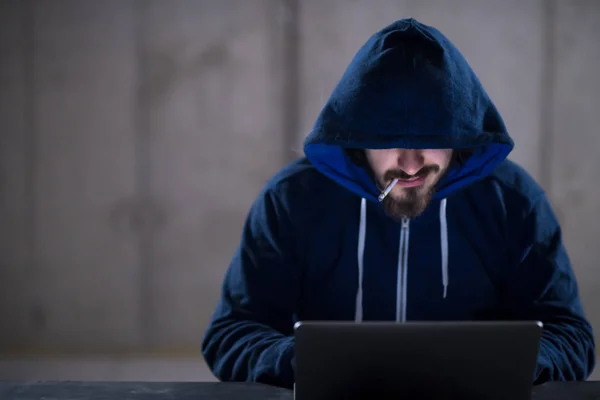 Jovem hacker usando computador portátil enquanto trabalhava no escritório escuro — Fotografia de Stock