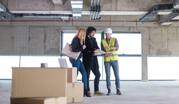 Arquiteto mostrando planos de design de casa para um jovem casal — Fotografia de Stock