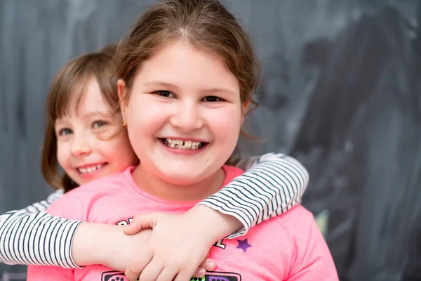 Bambine che si abbracciano davanti alla lavagna — Foto Stock