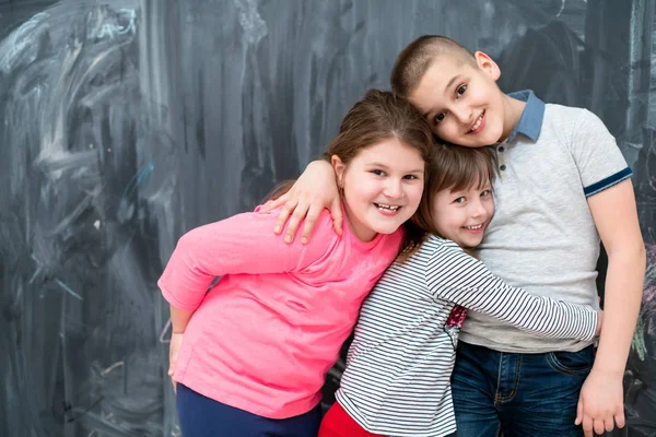 Groep kinderen knuffelen in de voorkant van schoolbord — Stockfoto