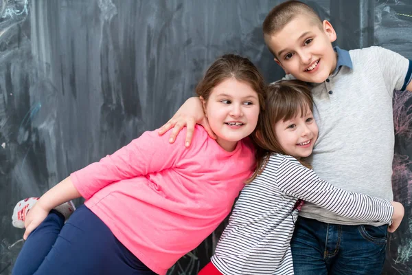 Groep kinderen knuffelen in de voorkant van schoolbord — Stockfoto