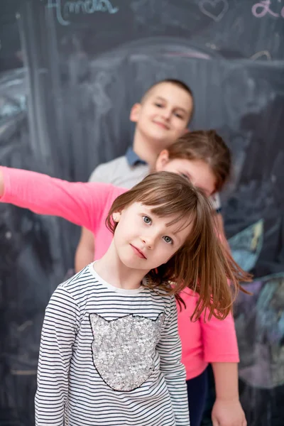 Group of kids standing in front of chalkboard — Stock Photo, Image