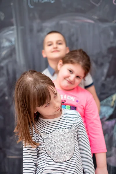 Group of kids standing in front of chalkboard — Stock Photo, Image