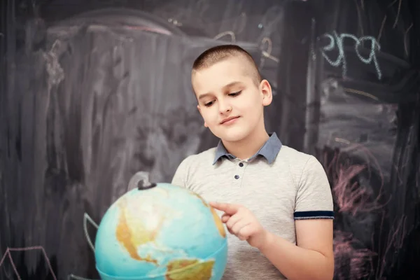 Αγόρι που χρησιμοποιεί σφαίρα της γης μπροστά από το chalkboard — Φωτογραφία Αρχείου