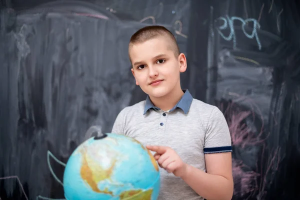 Niño usando globo de tierra delante de pizarra — Foto de Stock