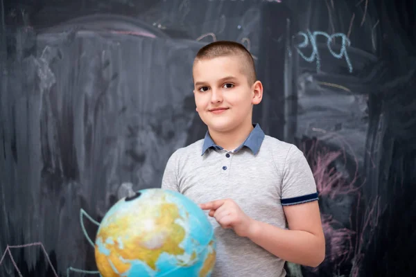 Niño usando globo de tierra delante de pizarra — Foto de Stock