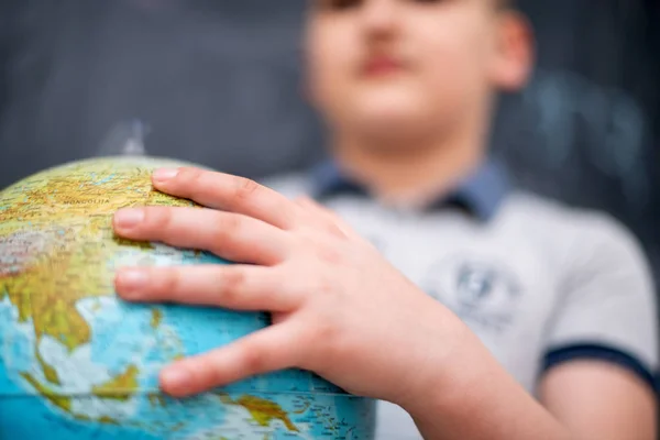 Boy using globe of earth in front of chalkboard — Stock Photo, Image