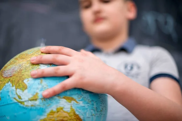 Boy using globe of earth in front of chalkboard — Stock Photo, Image