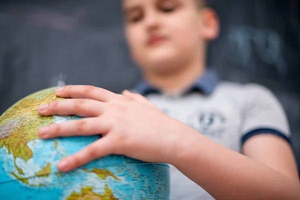 Boy using globe of earth in front of chalkboard — Stock Photo, Image