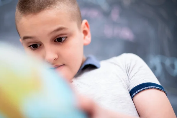 Ragazzo utilizzando globo di terra davanti alla lavagna — Foto Stock