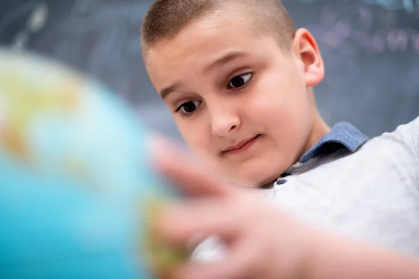 Chlapec pomocí zeměkoule před tabulí — Stock fotografie