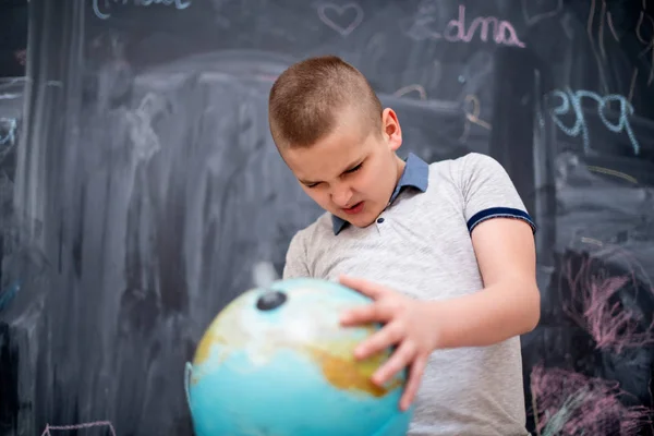 Menino usando globo de terra na frente do quadro — Fotografia de Stock