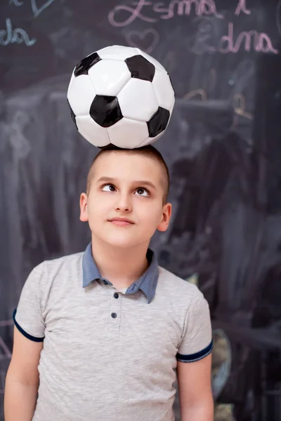 Menino feliz segurando uma bola de futebol em sua cabeça — Fotografia de Stock