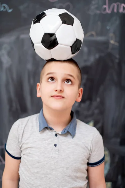 Menino feliz segurando uma bola de futebol em sua cabeça — Fotografia de Stock