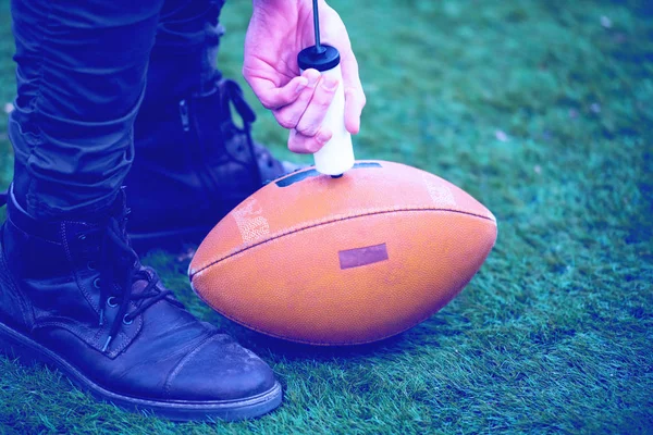 Uomo pompaggio aria in palla da calcio americano — Foto Stock