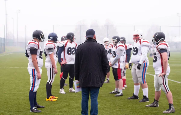 Giocatori di football americano discutendo strategia con allenatore — Foto Stock