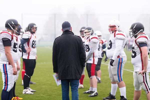 Jogadores de futebol americano discutindo estratégia com o treinador — Fotografia de Stock
