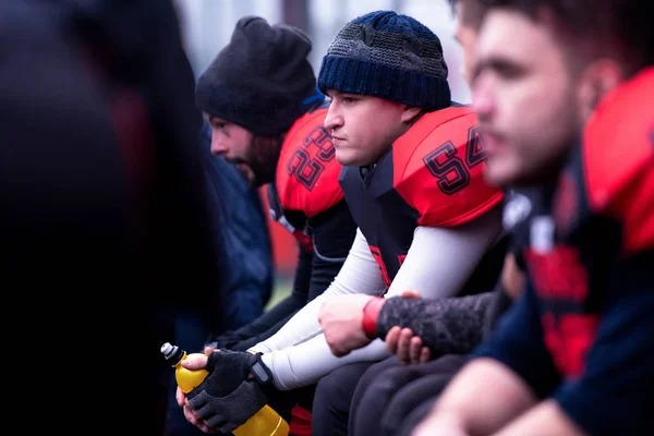 Jogador de futebol americano descansando com companheiros de equipe — Fotografia de Stock