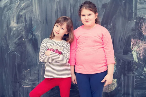 Portrait of little girls in front of chalkboard — Stock Photo, Image