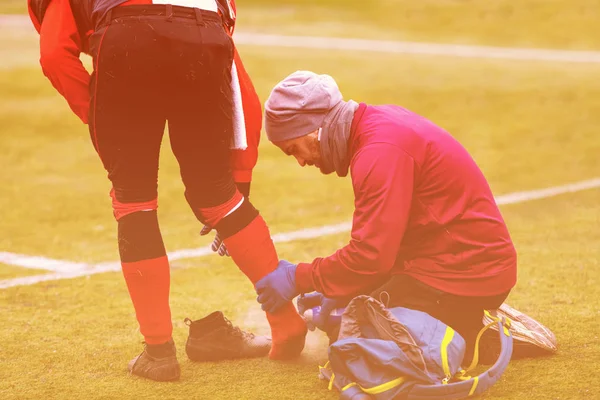 Sports doctor using freezing spray while treating injured sportm — Stock Image Sports doctor using freezing spray while treating injured sportm Royalty Free Stock Images