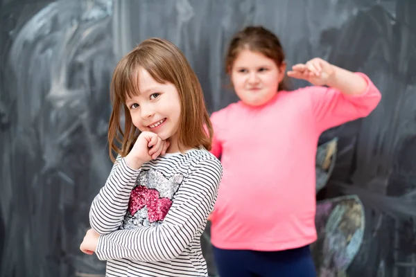 Portrait of little girls in front of chalkboard — Stock Photo, Image