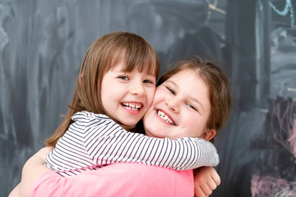 Meninas abraçando na frente do quadro — Fotografia de Stock
