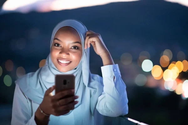 Ung Muselman kvinna på gata på natten användande telefon — Stockfoto