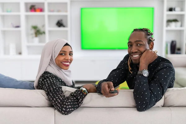 Afrykańska para siedzi na kanapie oglądając telewizję razem — Zdjęcie stockowe