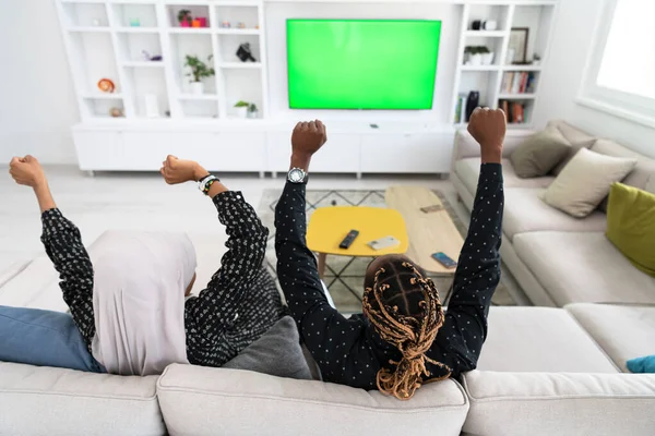 Pareja africana sentada en un sofá viendo televisión juntos — Foto de Stock