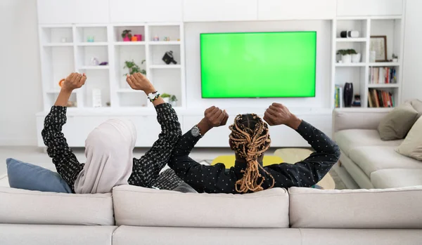 Pareja africana sentada en un sofá viendo televisión juntos —  Fotos de Stock