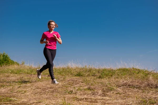 Молодая женщина бегает в солнечный день на летних горах — стоковое фото