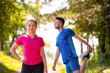 Genç çift ısınıyor ve doğada güneşli bir günde geriniyor.