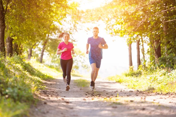 Mladý pár jogging na slunný den v přírodě — Stock fotografie