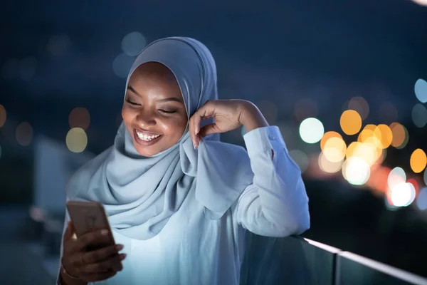 Mujer musulmana joven en la calle por la noche usando el teléfono — Foto de Stock