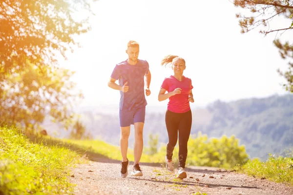 Jovem casal jogging no dia ensolarado na natureza — Fotografia de Stock