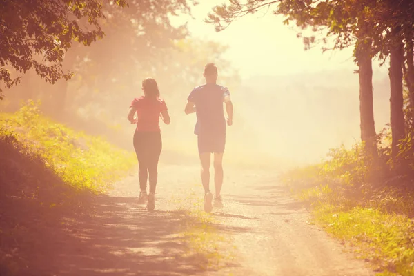 年轻夫妇在阳光明媚的日子在大自然中慢跑 — 图库照片