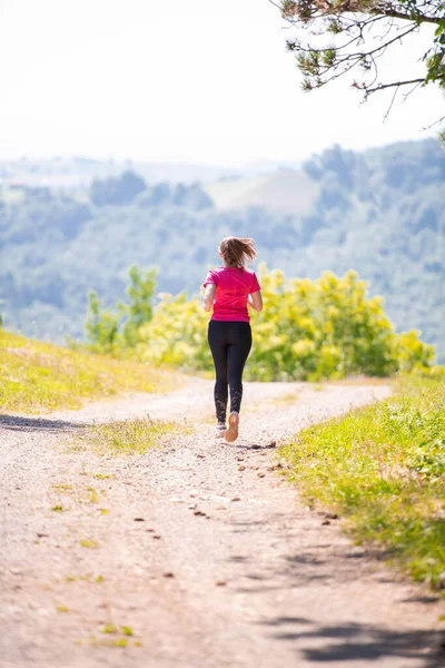 Jonge vrouw joggen op zonnige dag in de natuur — Stockfoto