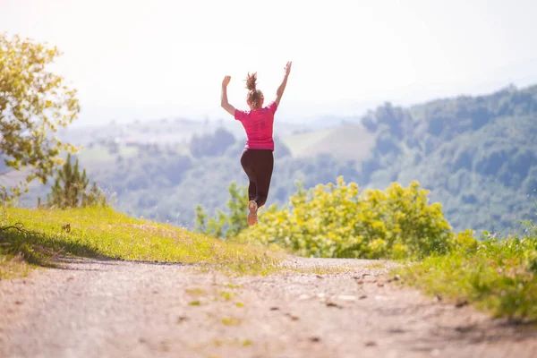 Mladá žena jogging na slunný den v přírodě — Stock fotografie