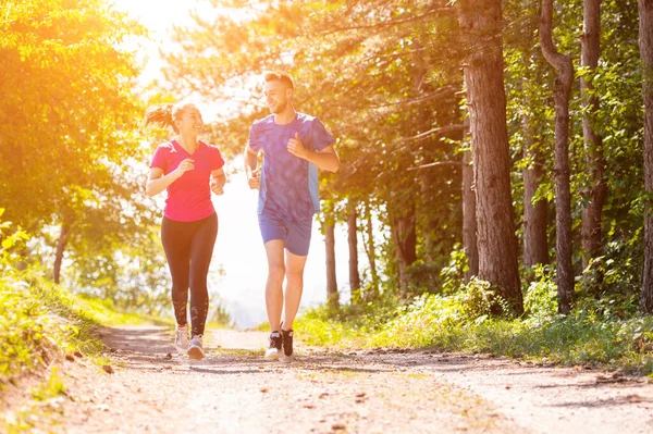 Jong paar joggen op zonnige dag in de natuur — Stockfoto