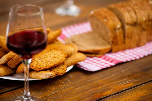 Glass of red wine and toasted bread on wooden table — Stock Photo, Image