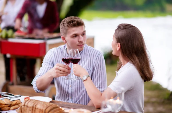 Happy couple toasting red wine glass during french dinner party — Stock Photo, Image
