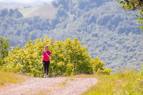 Młoda kobieta jogging w słoneczny dzień na łonie natury — Zdjęcie stockowe