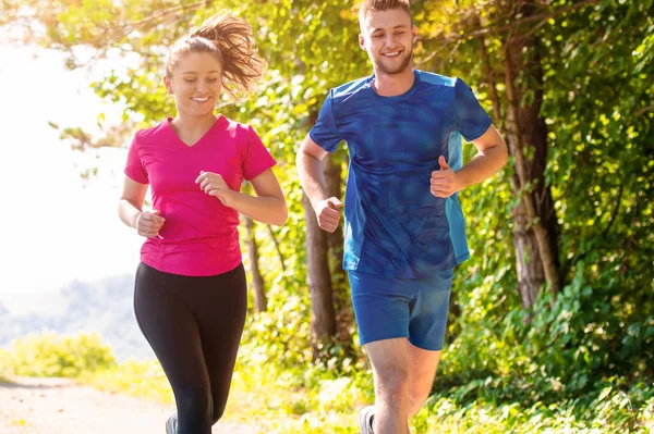 Jovem casal jogging no dia ensolarado na natureza — Fotografia de Stock