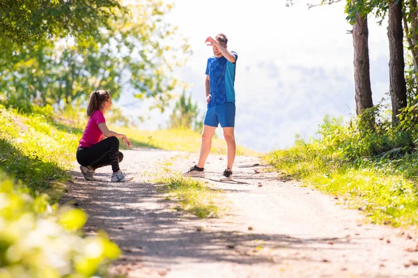 Pareja joven calentándose y estirándose en el día soleado en la naturaleza — Foto de Stock