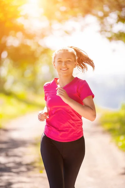 Mladá žena jogging na slunný den v přírodě — Stock fotografie