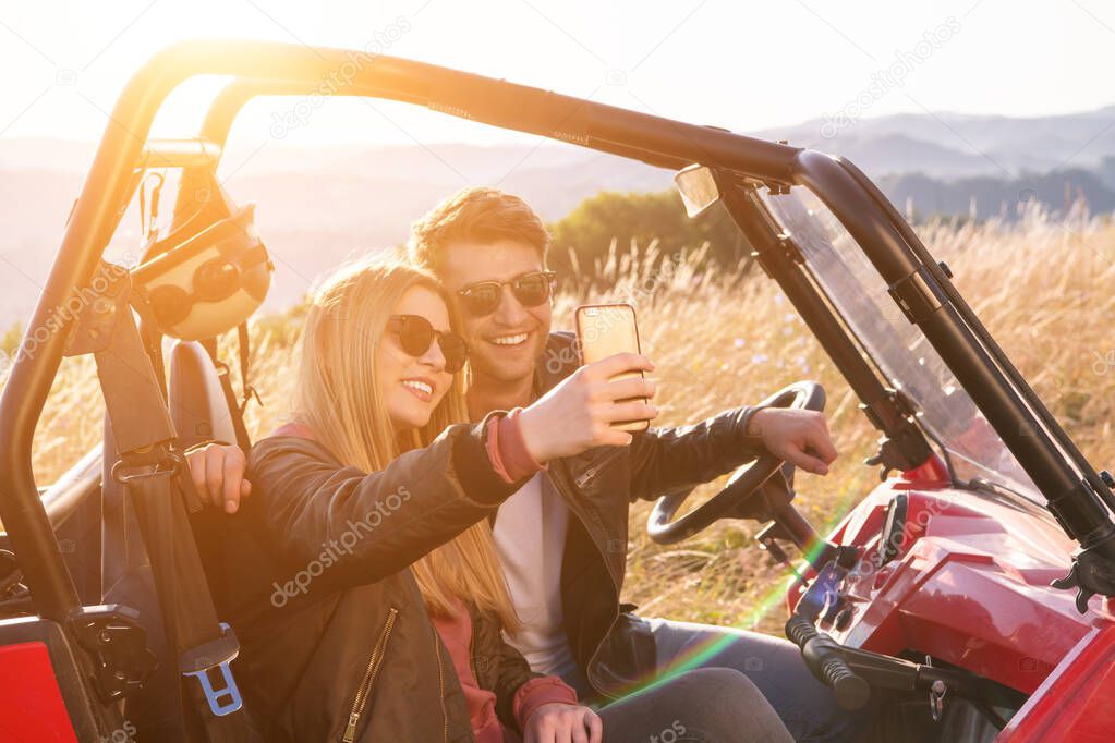 young couple taking selfie picture while driving a off road bugg