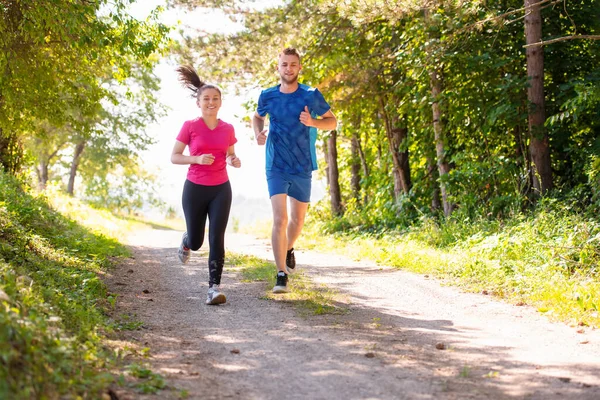 Unga par jogga på solig dag i naturen — Stockfoto